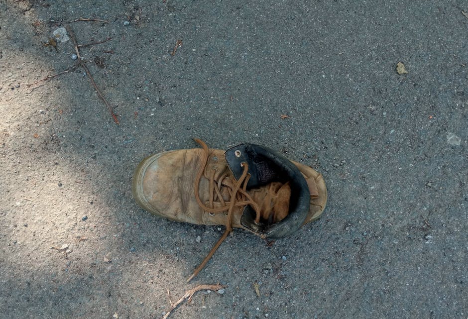 A single worn brown leather boot with laces on a paved surface in Porta Westfalica, Germany.