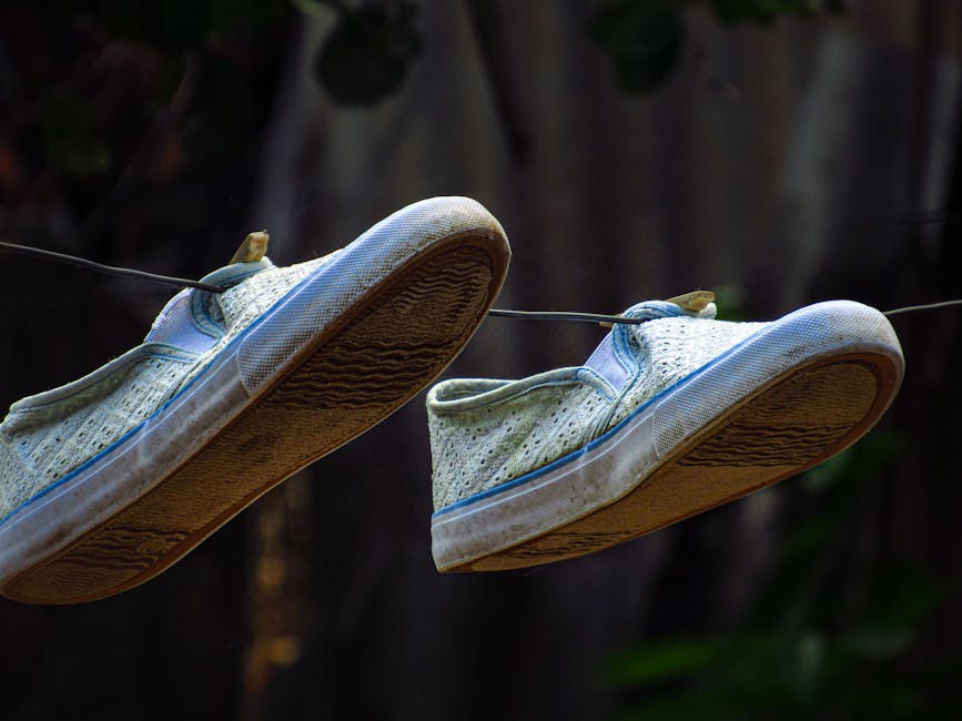 Close-up of worn canvas shoes hanging on a wire outdoors, showcasing texture.