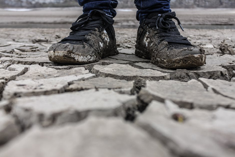 Close-up of muddy sneakers on cracked dry ground, symbolizing drought and resilience.