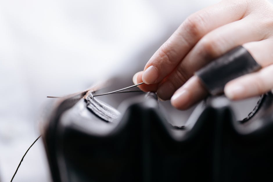 Close-up of a hand stitching leather, showcasing intricate craftsmanship and precision.