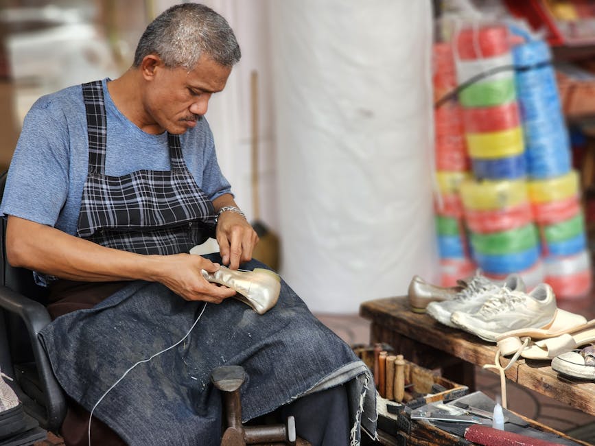 Artisan shoemaker working on shoes in his workshop with tools and materials around.
